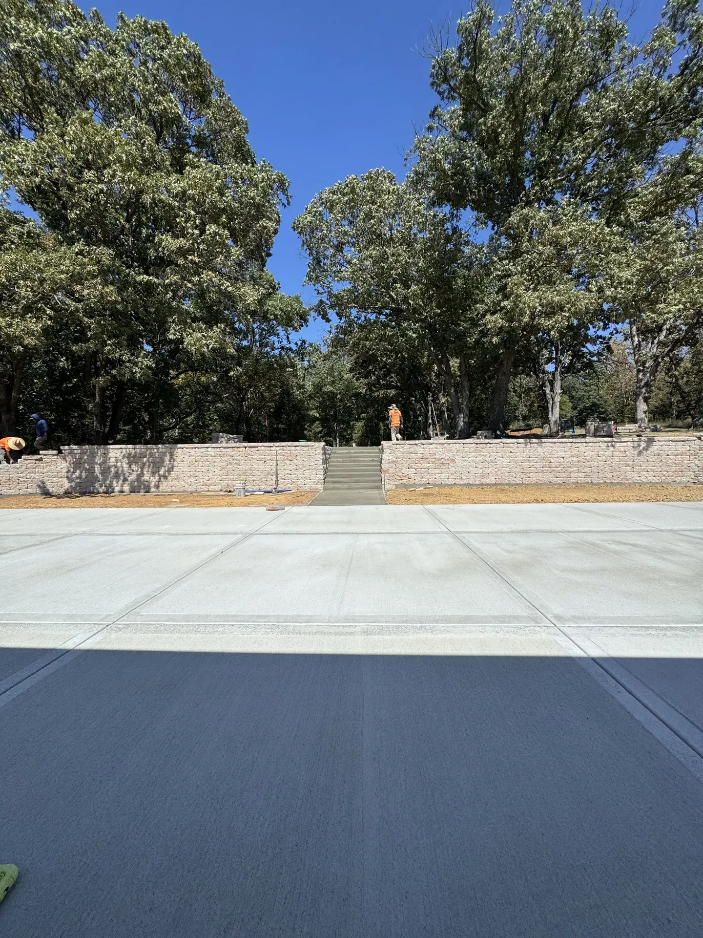 Large concrete patio with stone retaining walls and integrated steps