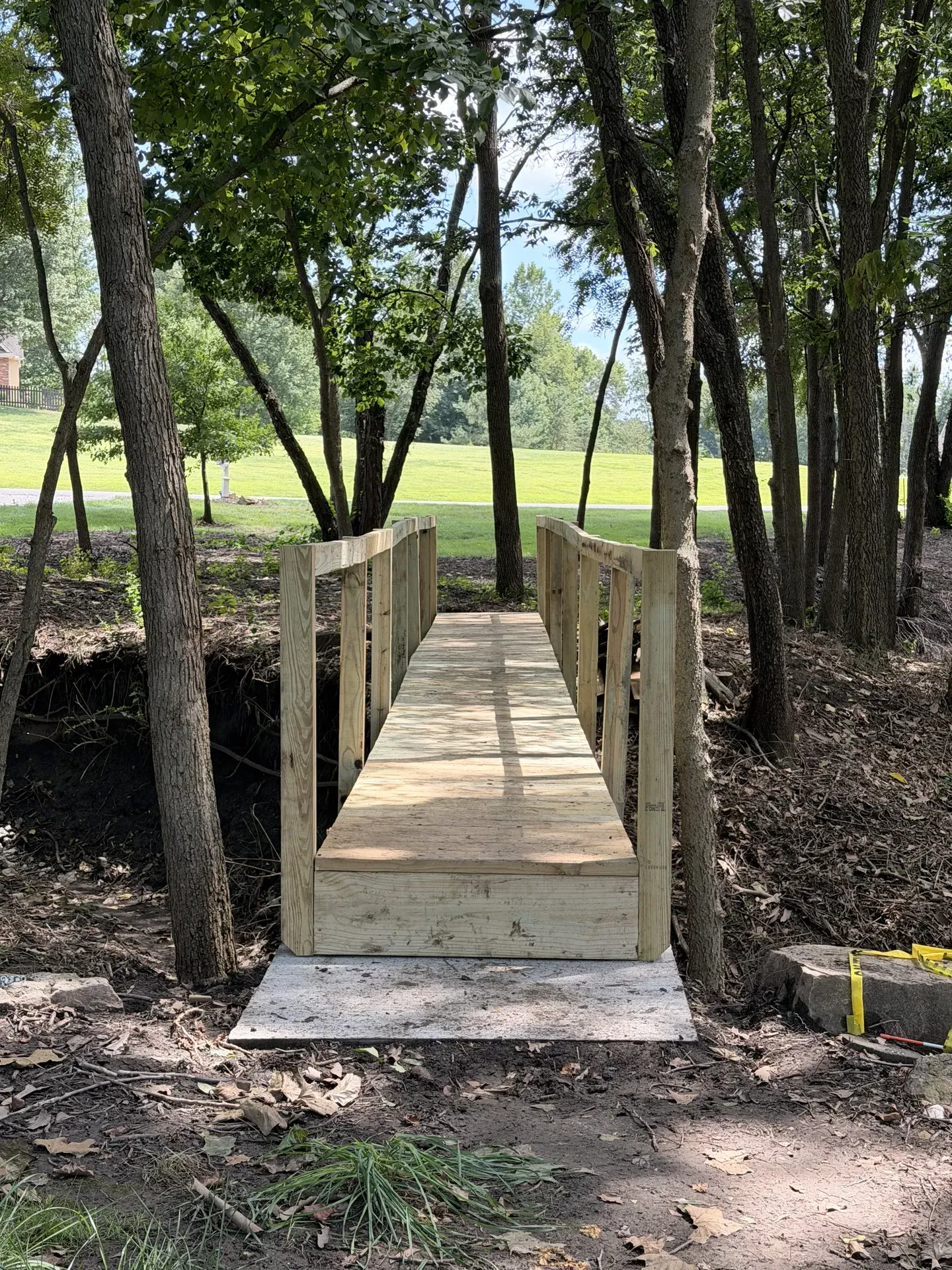 Decorative footbridge through a wooded landscape setting