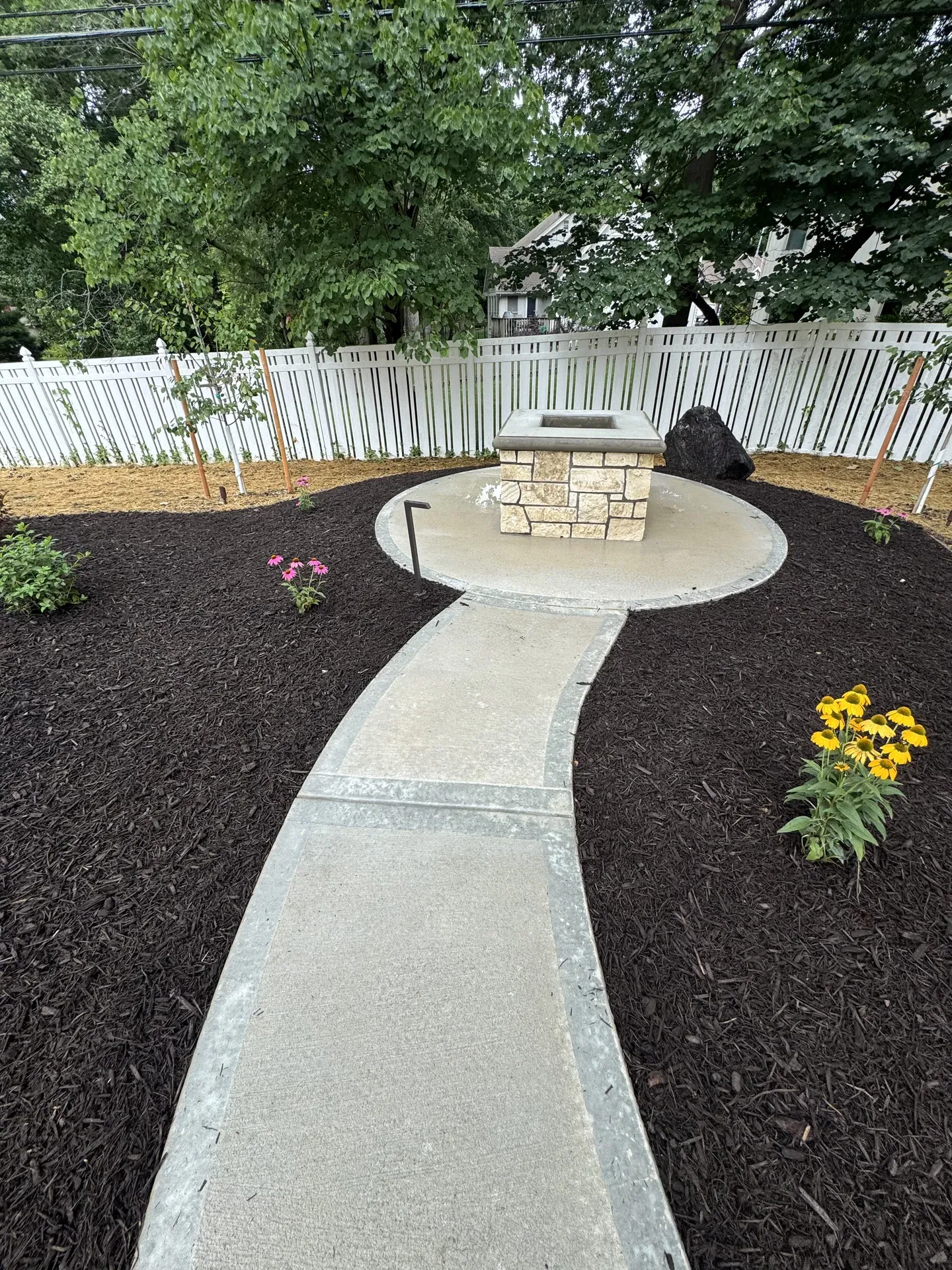 Outdoor path winding past fire pit and landscape plantings