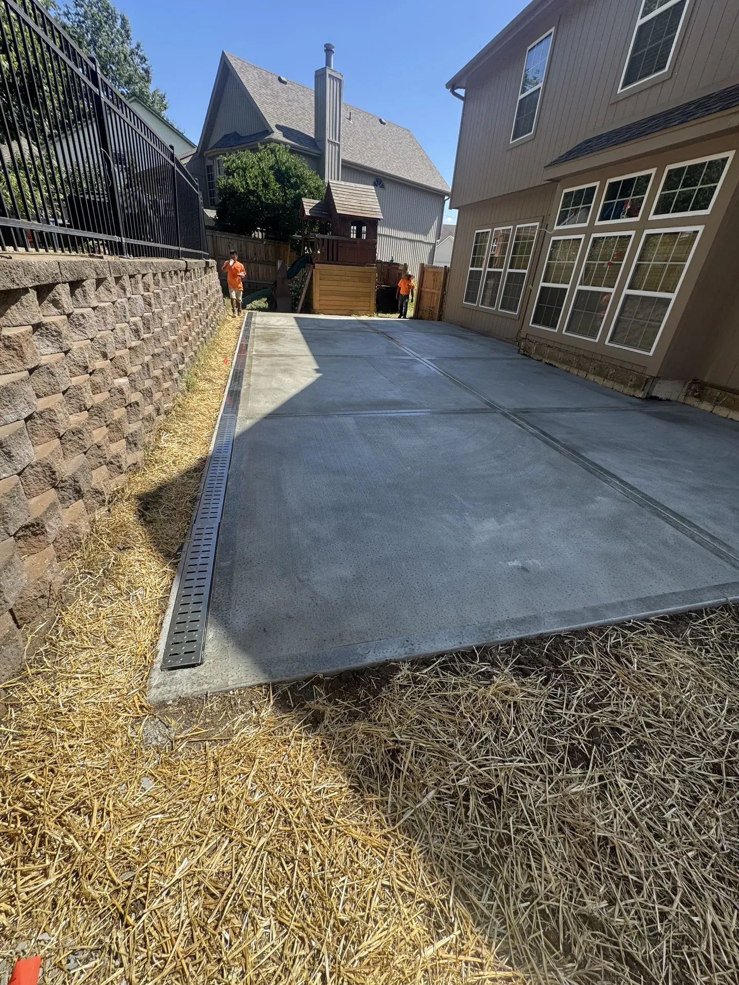 Concrete pad with channel drain alongside retaining wall