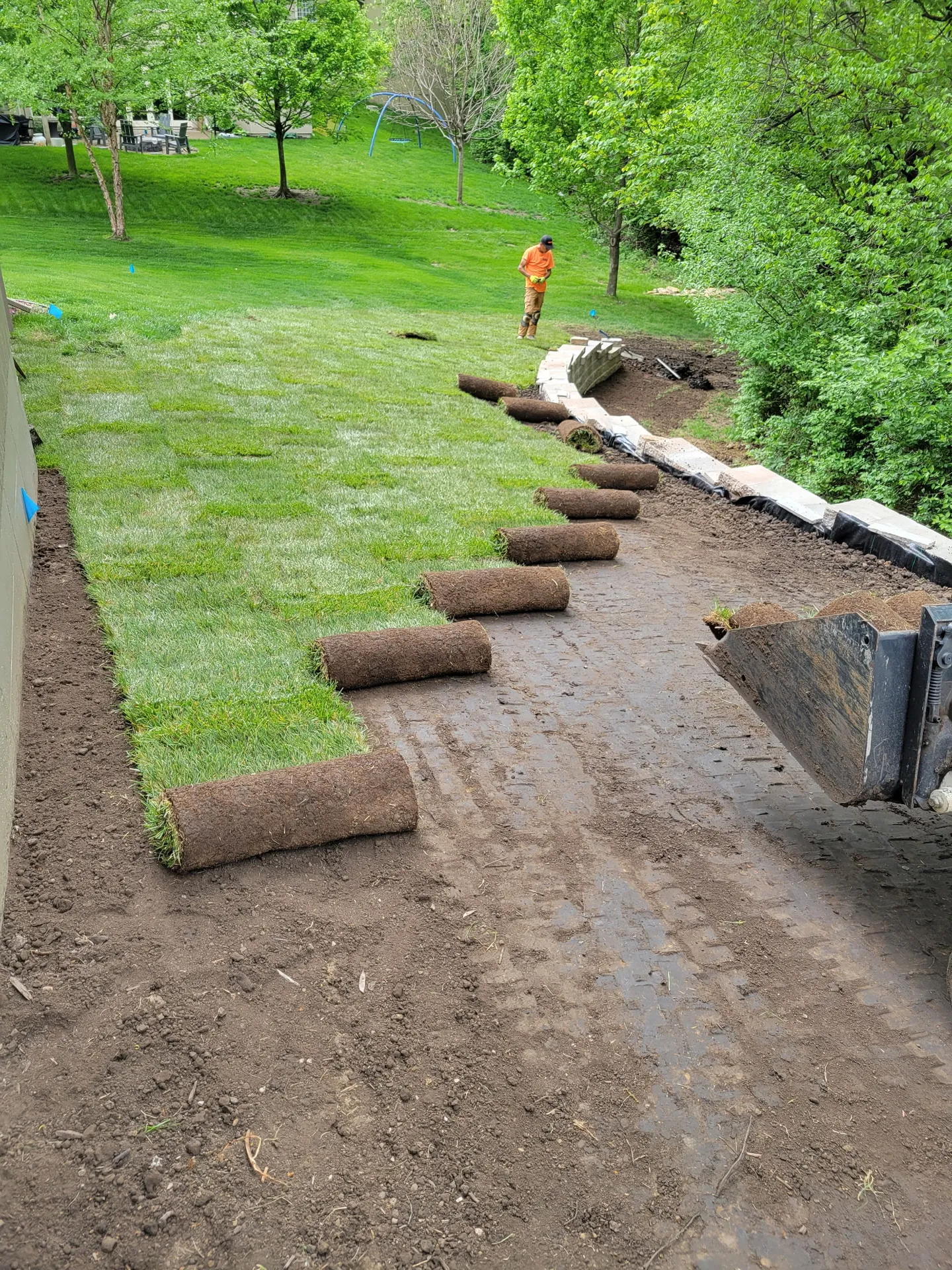 Crew installing sod alongside completed retaining wall